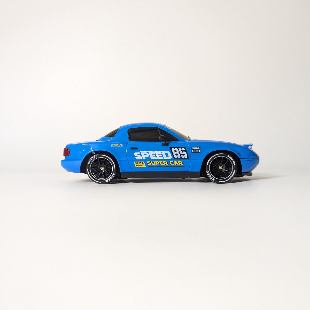 A blue die-cast model car with racing decals, including 'SPEED 85' and 'SUPER CAR', shown in profile against a plain white studio background.