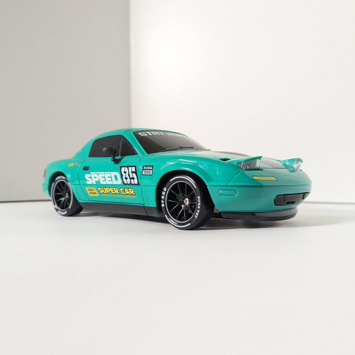 A turquoise and black die-cast model car with racing decals, including 'SPEED 89' and 'SUPER CAR', displayed on a clean white studio background.